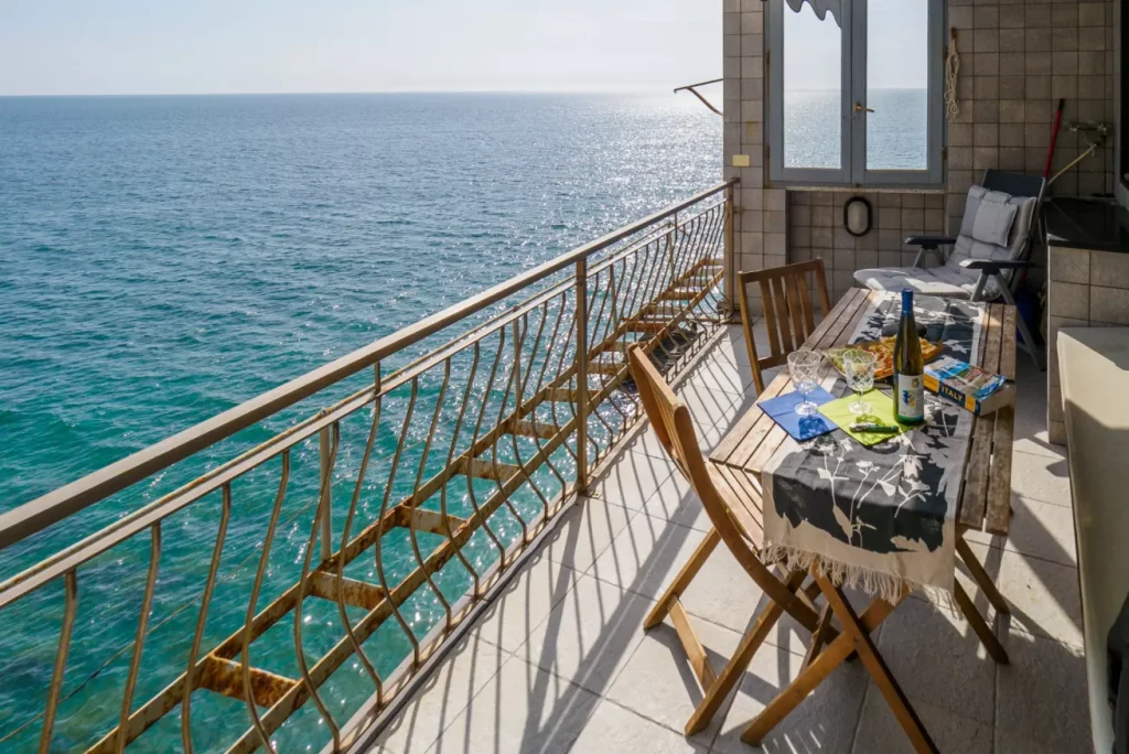 Set di sedie da balcone e tavolo in legno per due con vino e stuzzichini si affacciano sul Mar Ligure da Monterosso, vicino a La Casa del Gigante, offrendo viste panoramiche sull'oceano