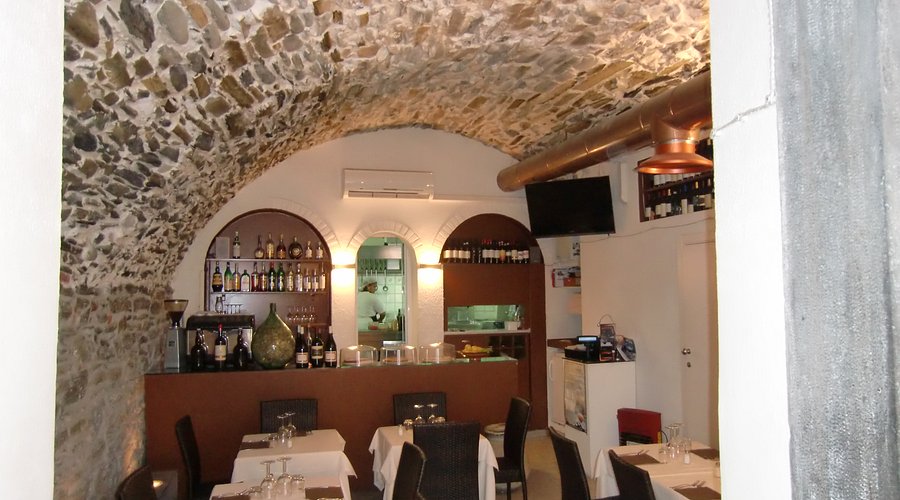 Il Grottino en Riomaggiore, un bar rústico de paredes de piedra y comedor con techo abovedado, botellas de vino en estantes y un ambiente acogedor de trattoria
