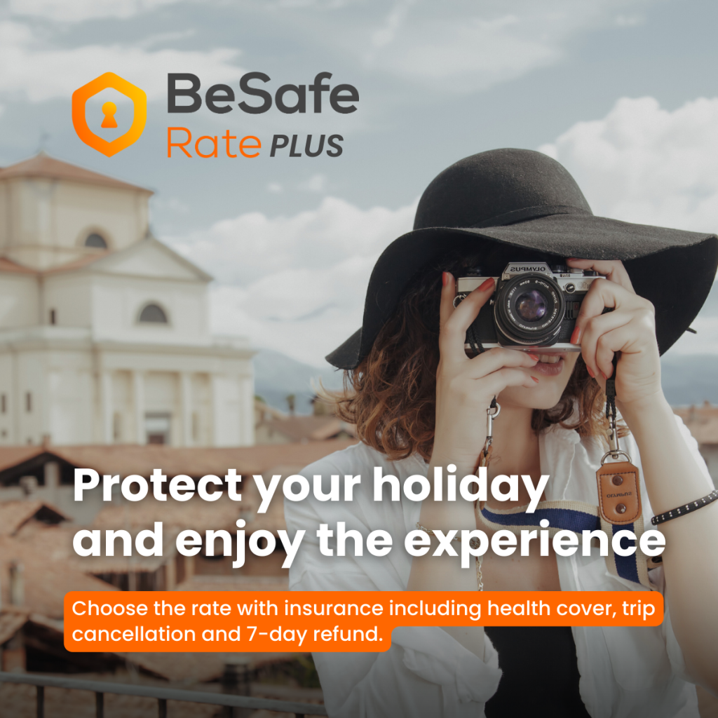 Logotipo de BeSafe Rate PLUS en naranja junto a un fotógrafo que lleva un sombrero negro de ala ancha y sostiene una cámara, con una localidad costera como fondo en Cinque Terre Riviera.