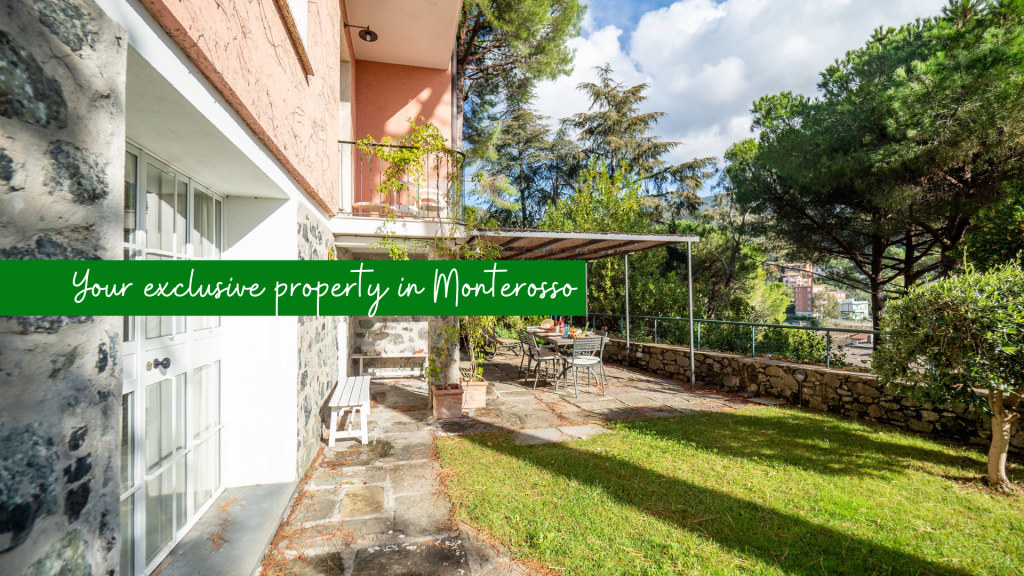 Pavona Imagine villa terrace in Monterosso with stone walls, green lawn, outdoor dining area, and surrounding trees under a bright sky.