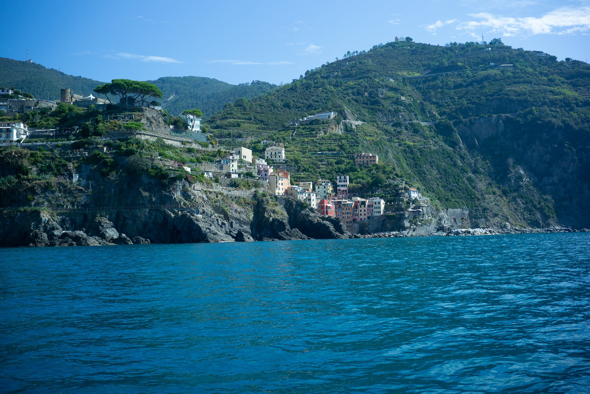 En Cinque Terre, el mar azul se funde con una costa rocosa en la que se asienta un pueblo enclavado en la ladera, con casas de colores, jardines en terrazas y sinuosos senderos que descienden en cascada hasta el agua.