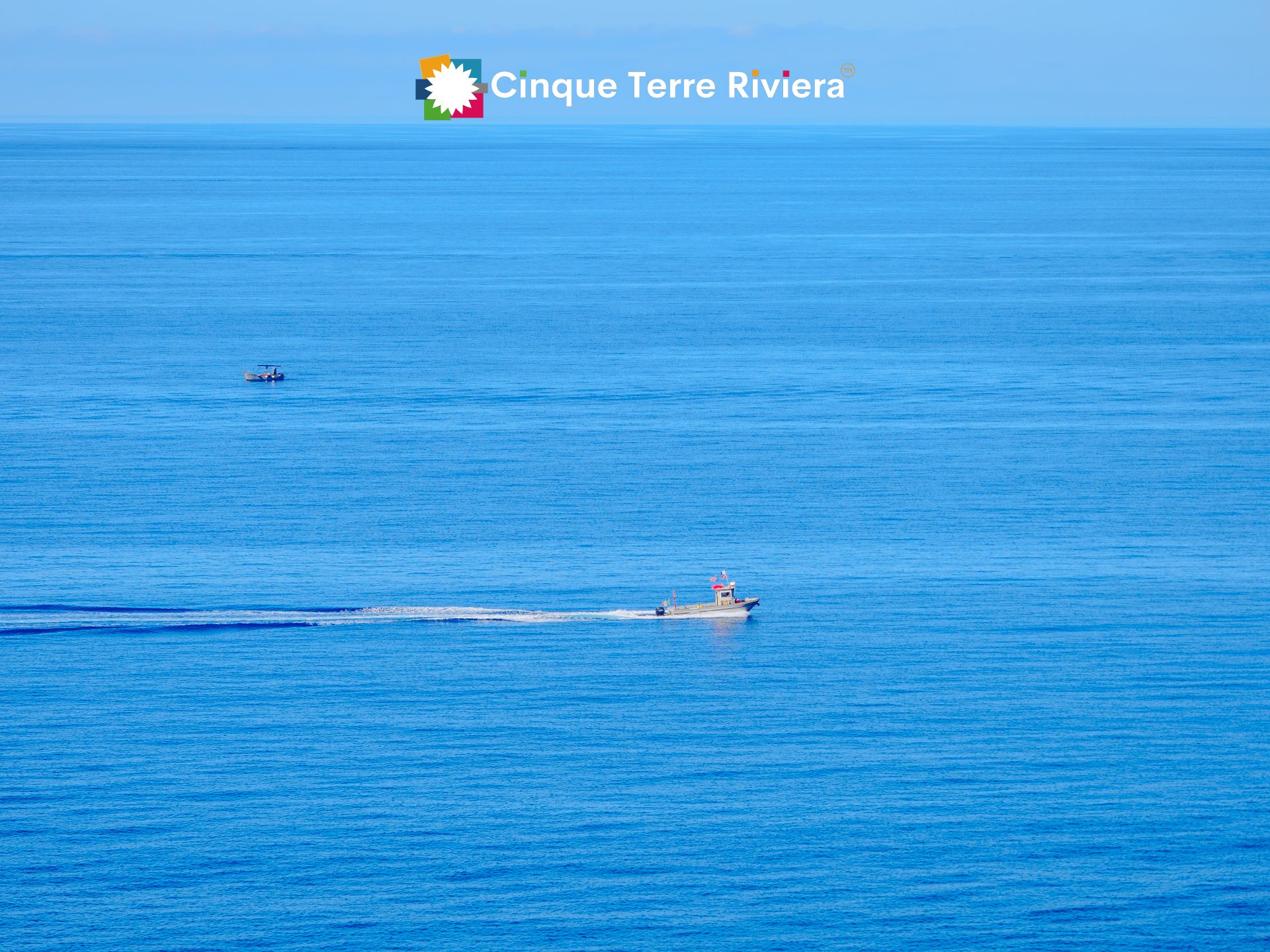Un pequeño barco cruzando el mar azul abierto entre los pueblos de las Cinque Terre en verano