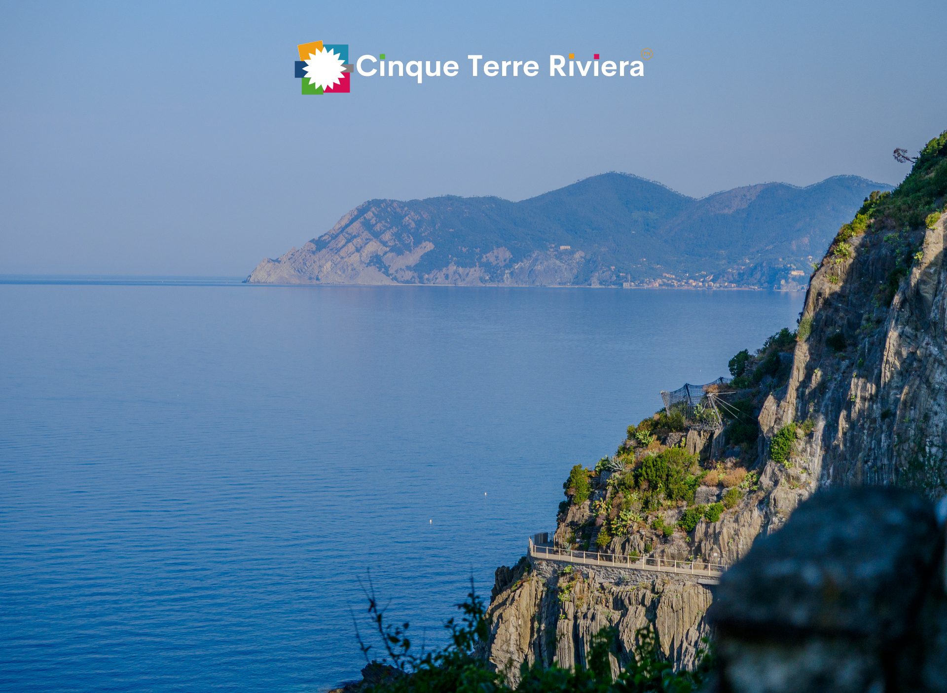 Suave luz de verano sobre la costa y el promontorio de las Cinque Terre vistos desde un sendero en la cima de un acantilado