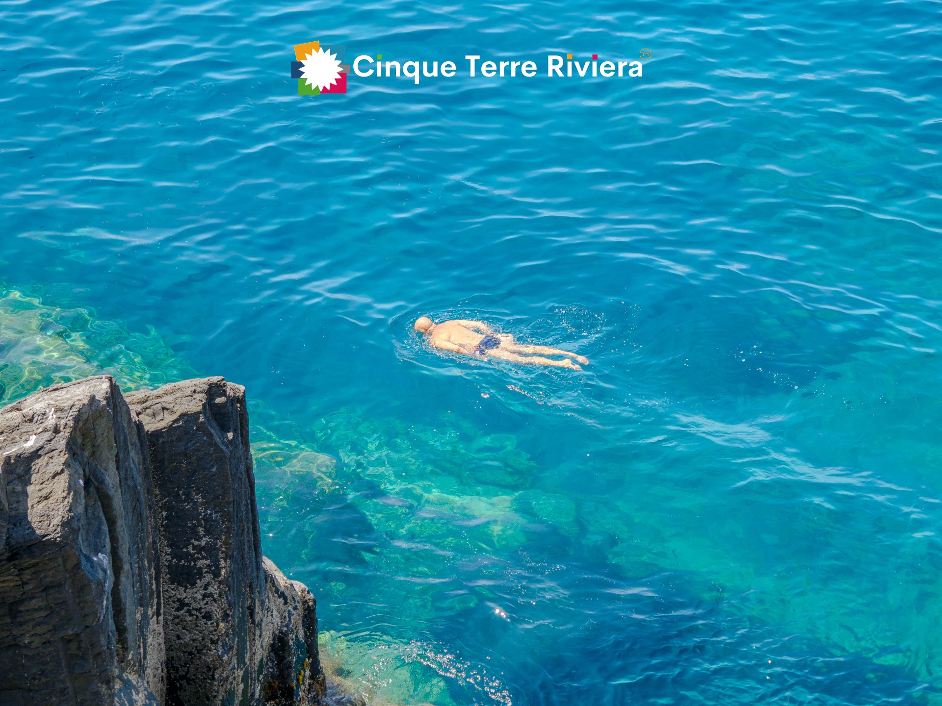 Un nadador solitario en el mar azul claro de las Cinque Terre, con espacio y serenidad a su alrededor